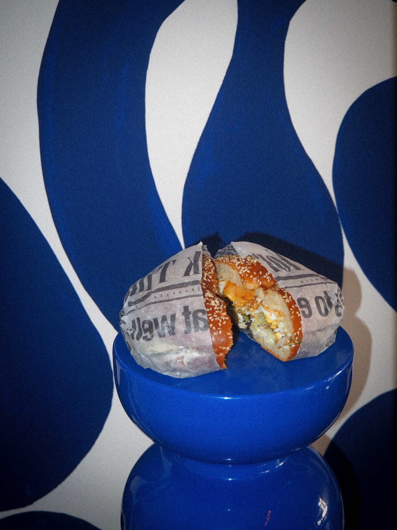 Bagel signature OZMO devant le mur bleu marine du snack à Saint-Raphaël